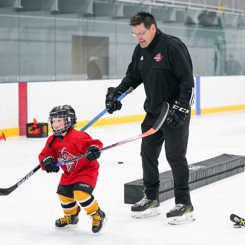 child and coach practicing hockey