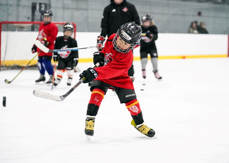 child hockey player shooting puck